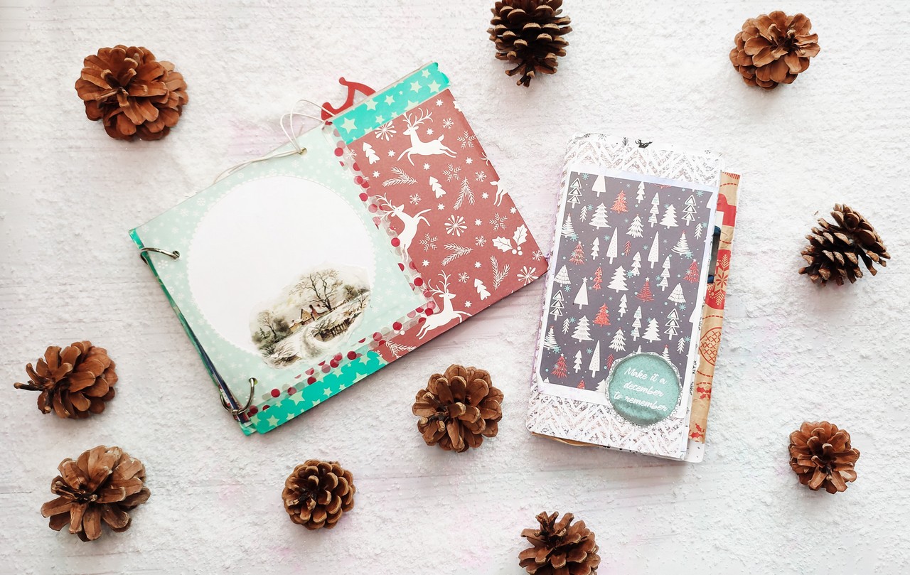 Okładki dwóch grudniowników na tle sztucznego śniegu i szyszek.